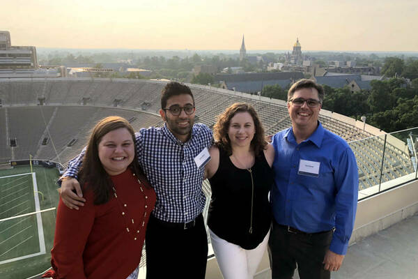 Four Data Science students posing from the roof of the stadium overlooking campus.
