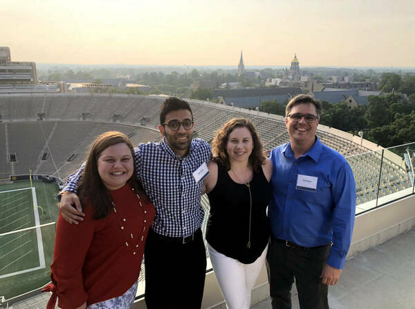 Four Data Science students posing from the roof of the stadium overlooking campus.