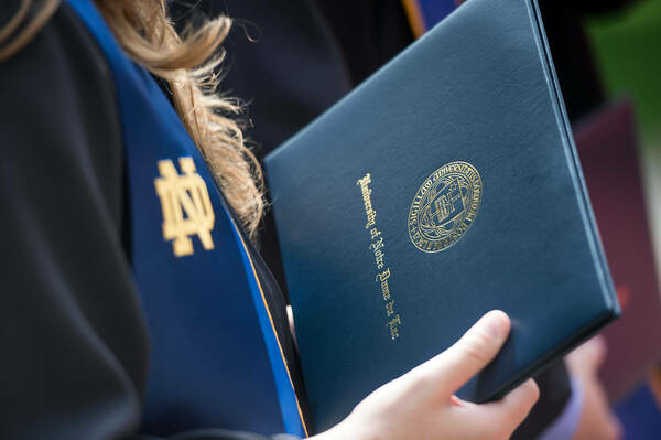 Graduating student holds a diploma.