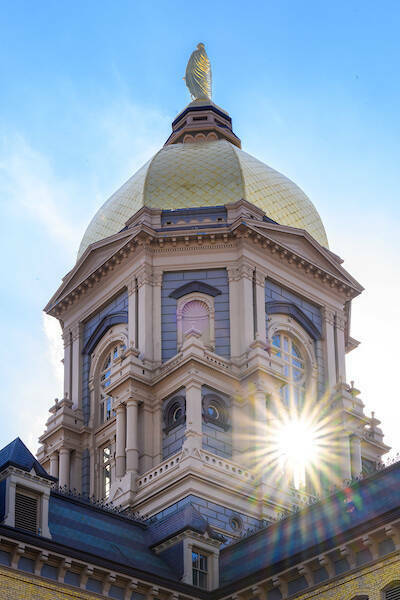 Notre Dame's golden dome with a bright reflecting glare in the bottom right corner.