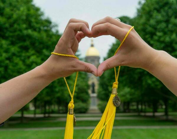 Graduates join hands as they make the shape of a heart in front of the Golden Dome shortly before the Commencement Ceremony. (Photo by Barbara Johnston/University of Notre Dame)